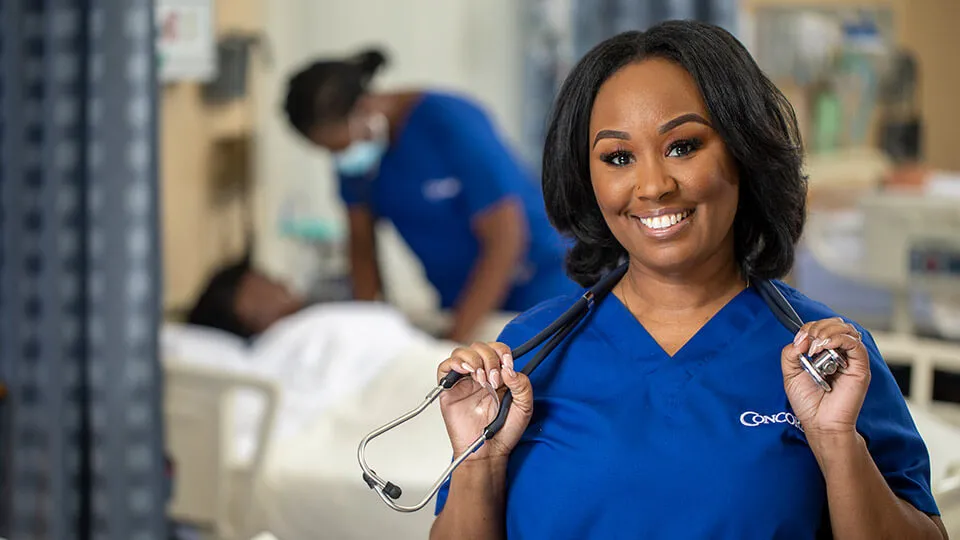 LPN in scrubs smiles while holding her stethoscope. LPN in scrubs smiles while holding her stethoscope.