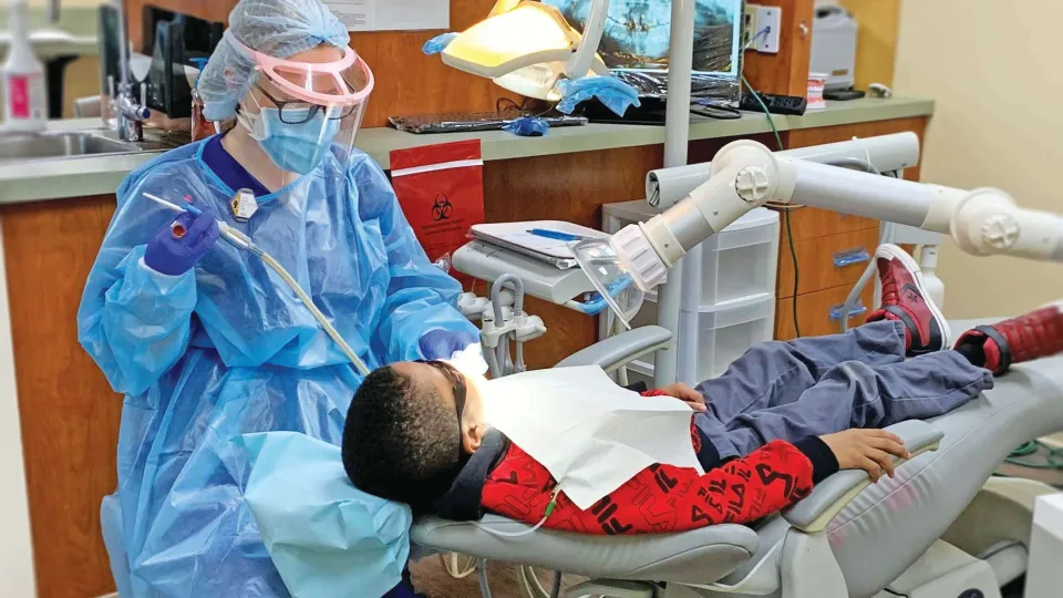 Concorde graduate performs pediatric dental cleaning during community event.