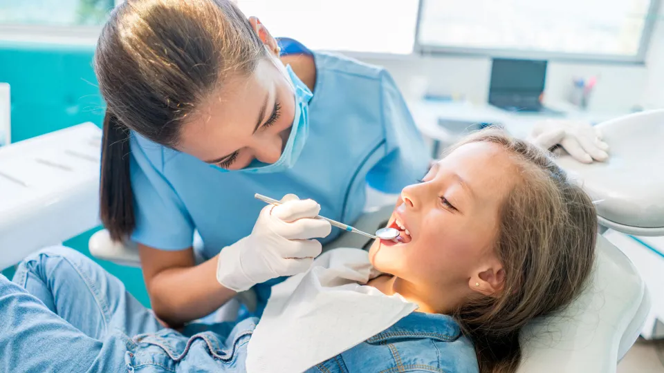 Dental assistant performs oral-cavity inspection on child with mouth-mirror Day in the life of a dental assistant as they performs oral-cavity inspection on child with mouth-mirror
