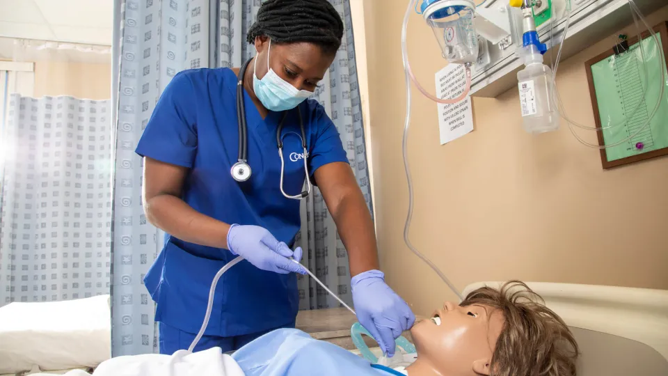 Nursing student practicing skills on a simulation mannequin. Nursing student practicing skills on a simulation mannequin.