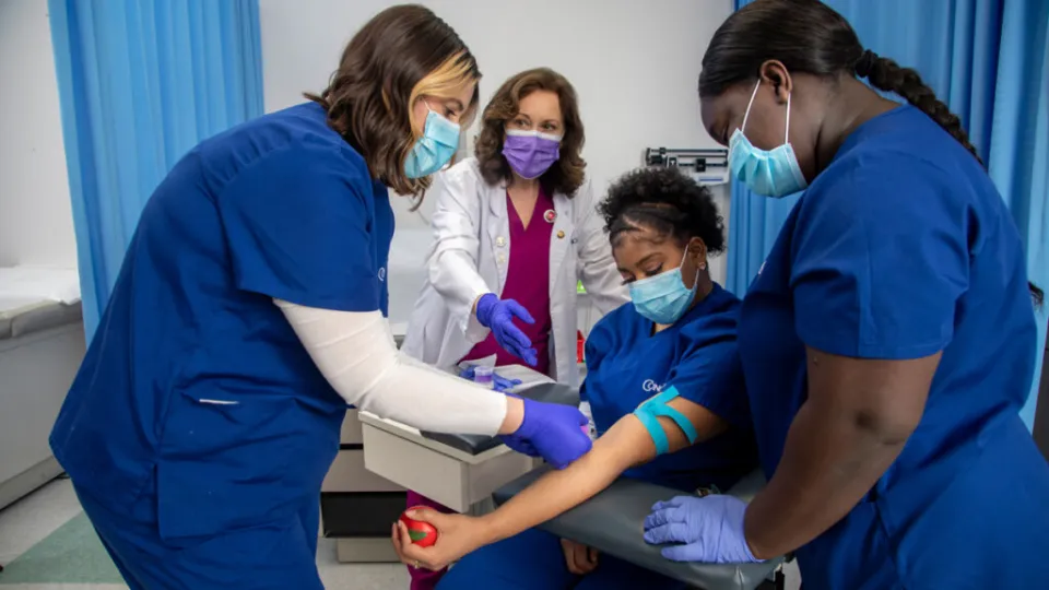 Medical assistant students practicing phlebotomy skills during hands-on training in a clinical education lab setting. Medical assistant students practicing phlebotomy skills during hands-on training in a clinical education lab setting.