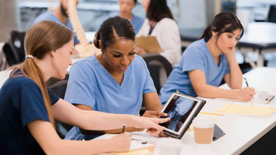 Radiologic technology students review spinal X-ray on tablet during class, preparing for hands-on healthcare careers