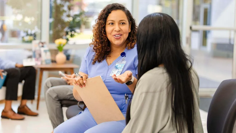 Medical office specialist speaking with patient in a clinic waiting room, highlighting the role's communication and support duties Medical office specialist speaking with patient in a clinic waiting room, highlighting the role's communication and support duties