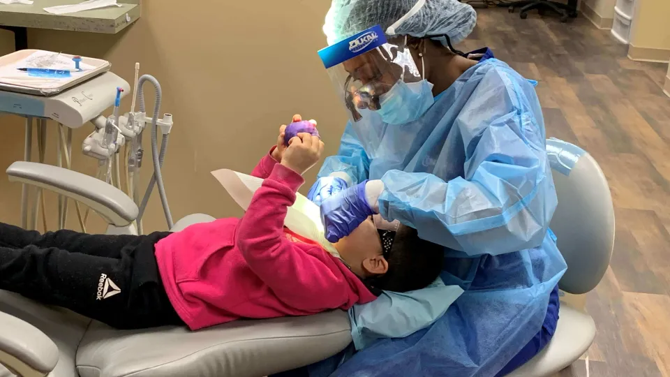 Dental Hygiene student performing dental cleaning on child under Dentist supervision