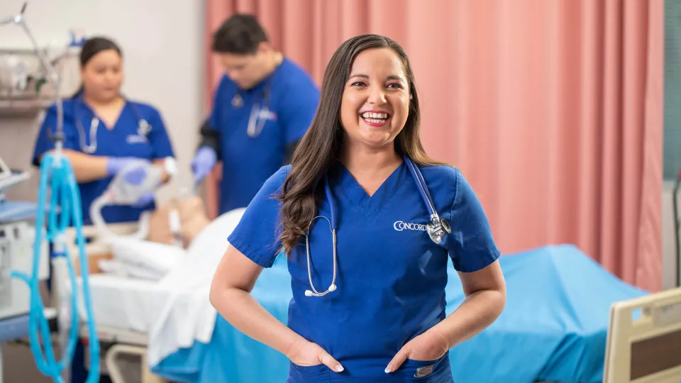 Concorde student smiling as others study respiratory therapy in the background Concorde student smiling as others study respiratory therapy in the background