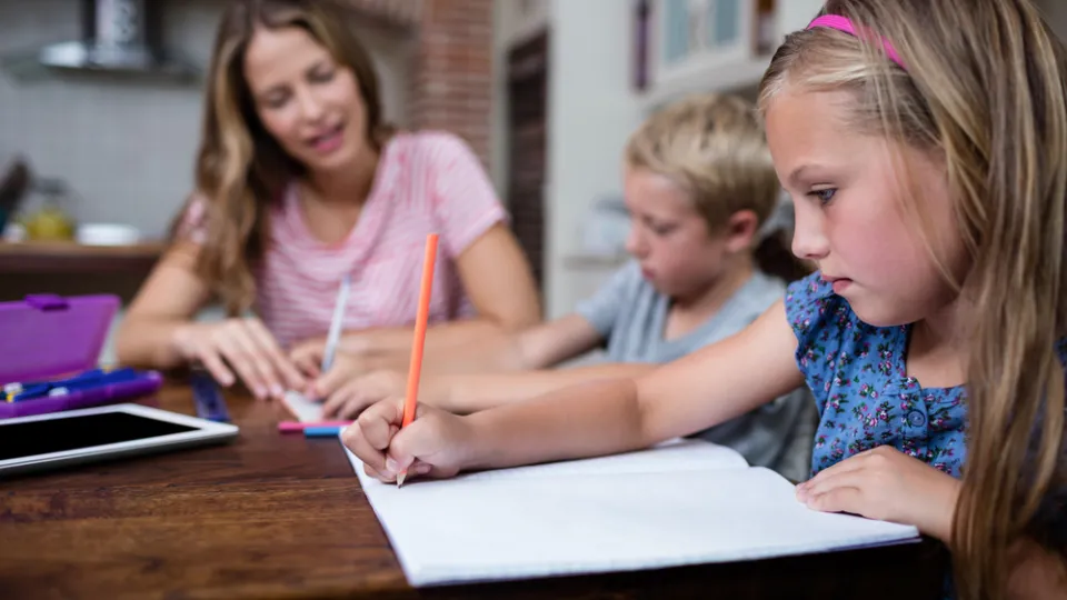 Group of five students of different races sitting together in classroom looking attentively in books and notebooks doing project work. College mixed race students preparing for final exams togehter health care education