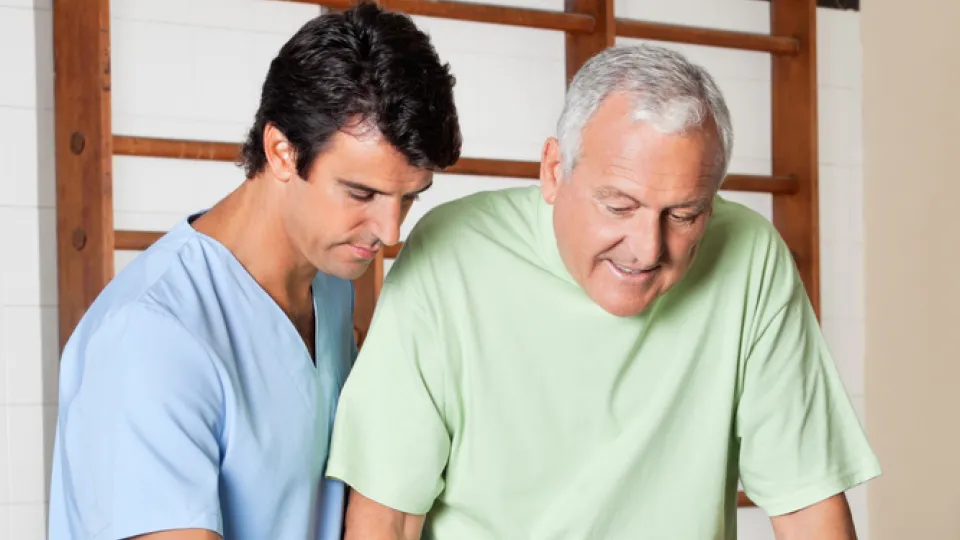 Therapist Assisting Senior Man To Walk With The Support Of Bars physical therapist assistant