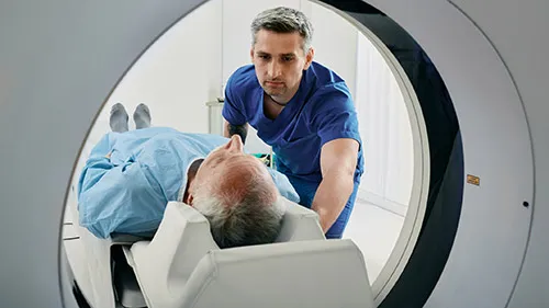A health care professional comforts his patient before he enters a CT scanner
