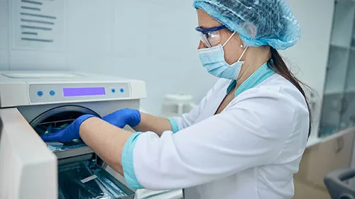 surgical technologist loading surgical instruments into an autoclave