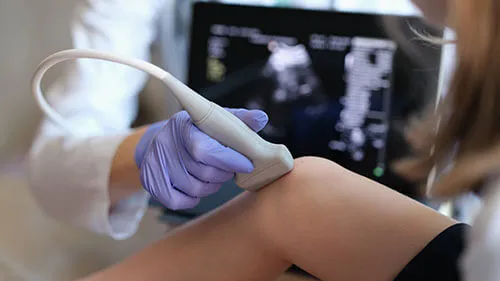 A diagnostic medical sonographer uses the scanning tool on patient's knee to look for potential injury.