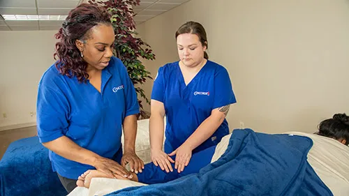 Student learning how to become a massage therapist under the supervision of teacher.
