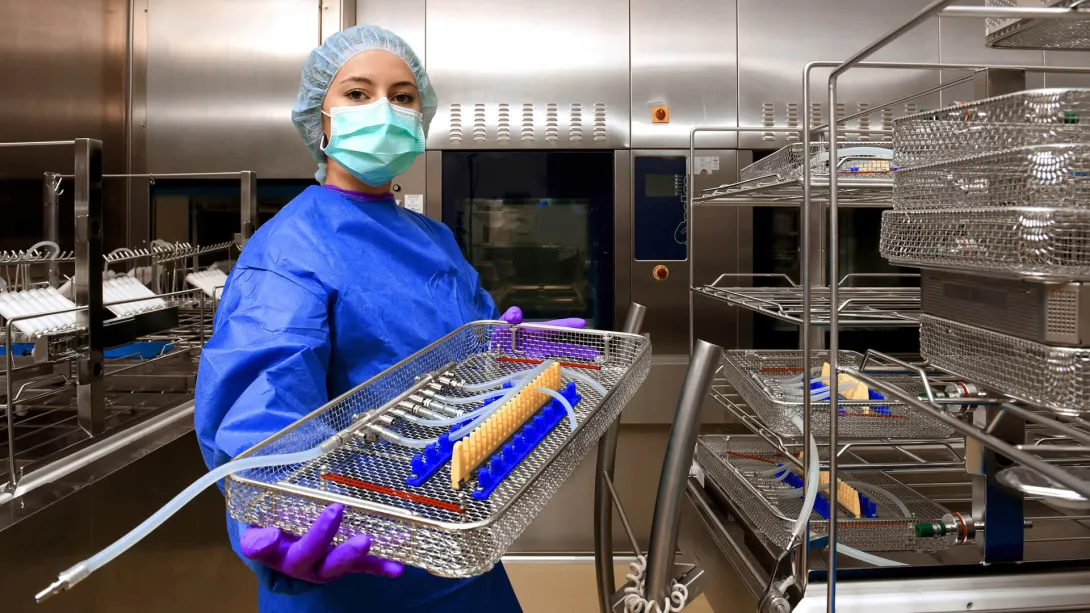 A young woman works in a hospital as a surgical technologist. She is dressed in special medical hygiene clothing and carries out hygiene disinfecting tasks.