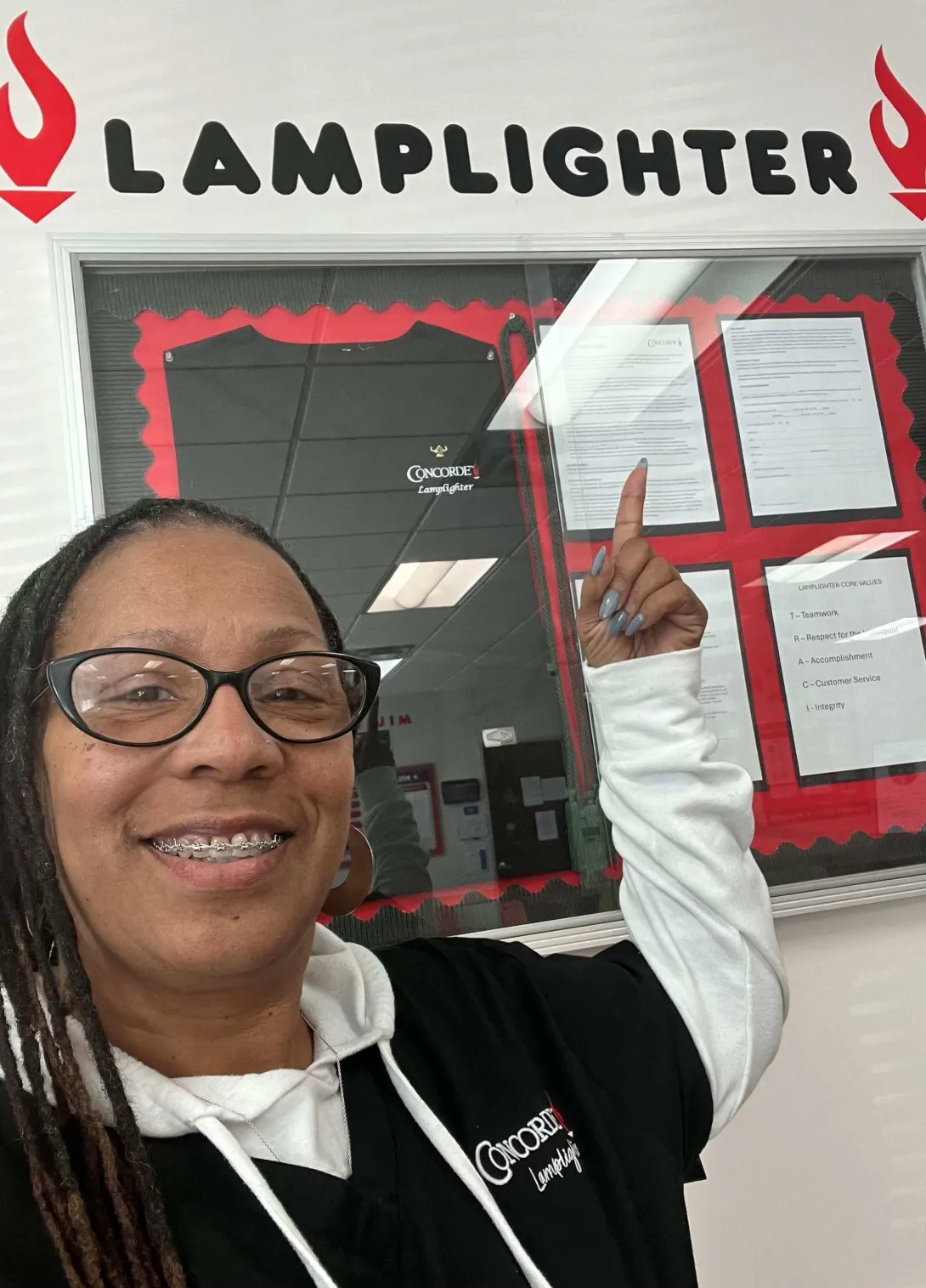 Chantel wearing her special Lamplighter scrubs standing next to a Lamplighter sign with her name on it.